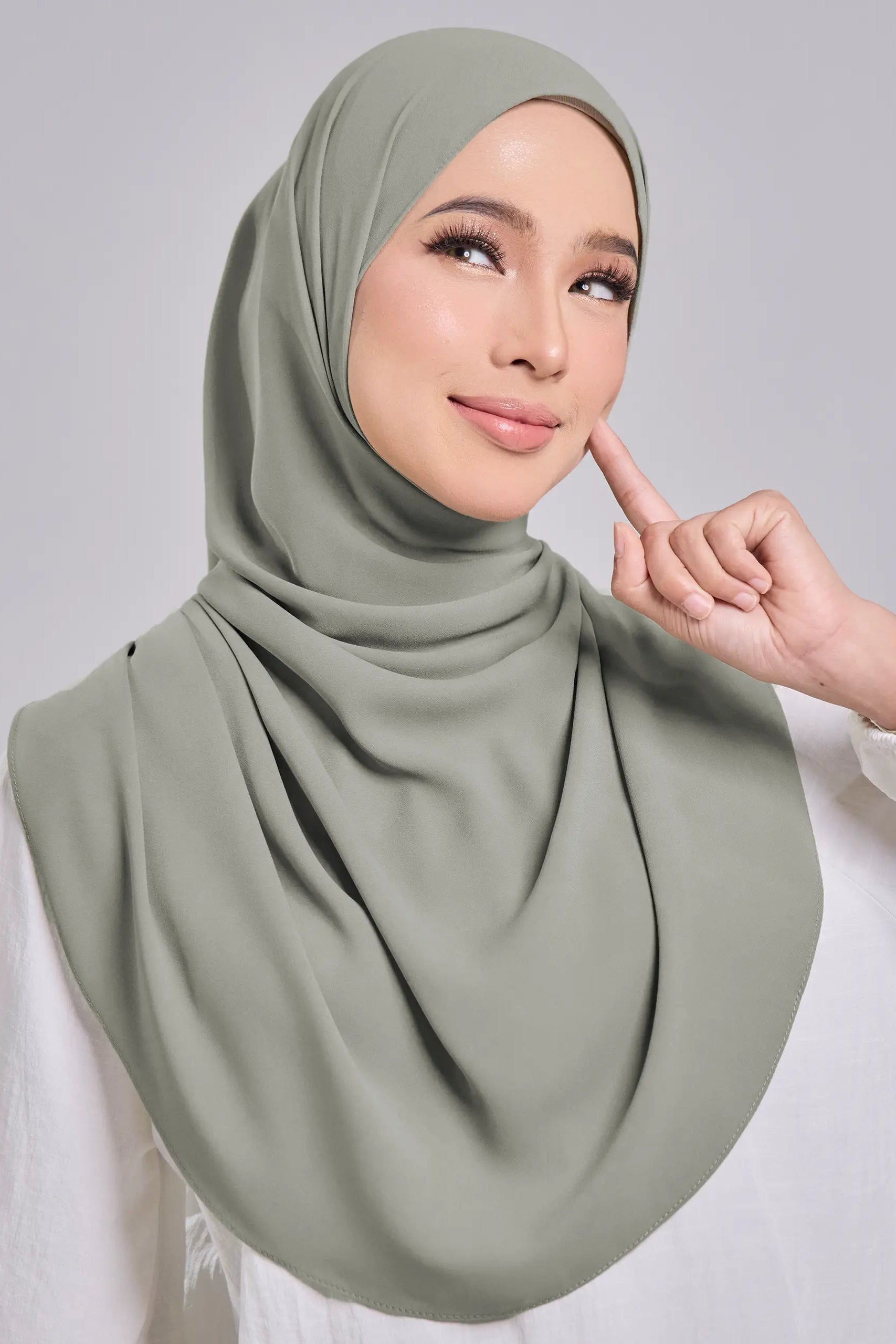 Woman wearing a green hijab against a gray background