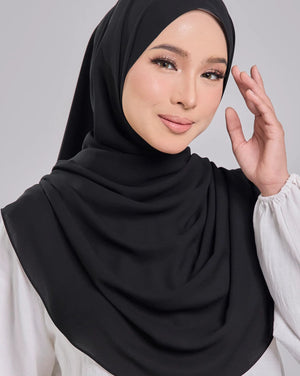 Woman wearing a black hijab and white top on a gray background