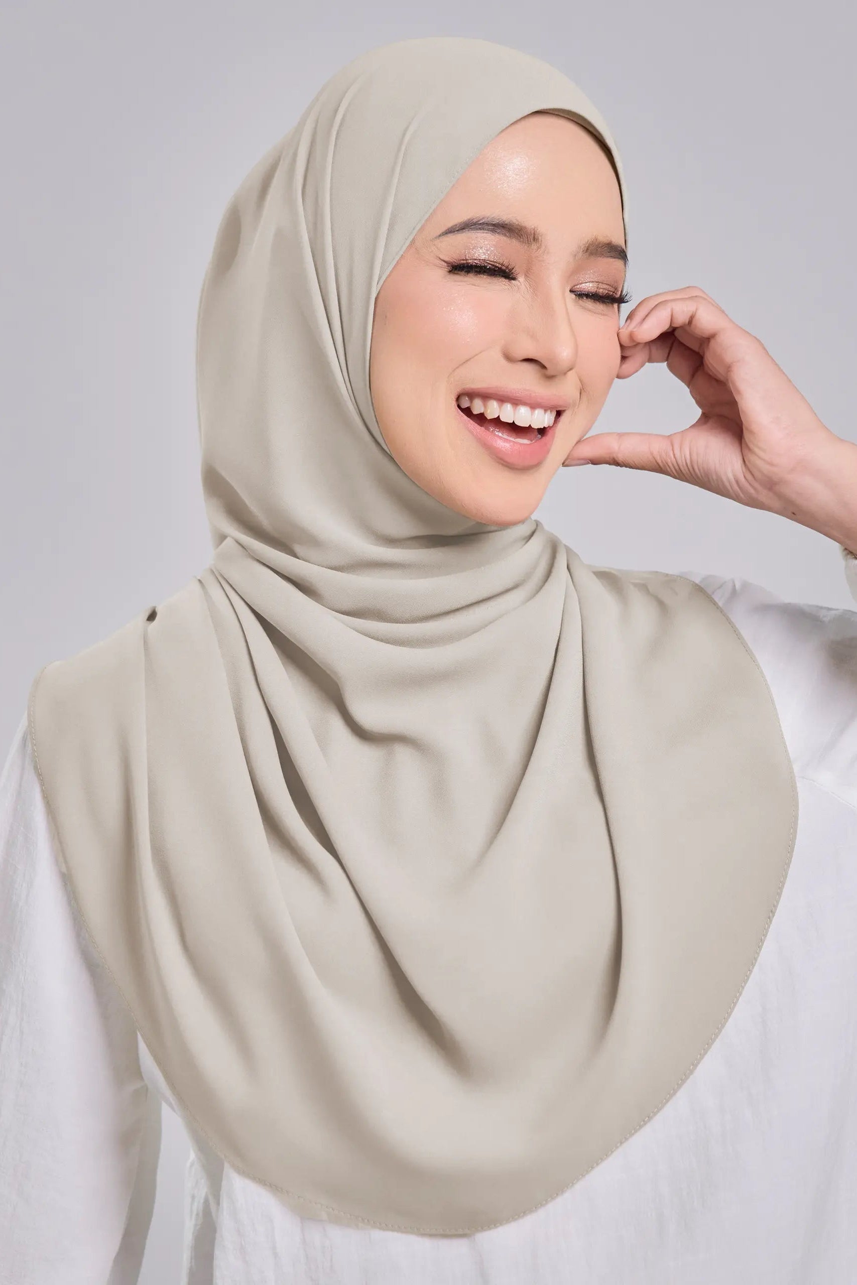 Woman wearing a beige hijab against a plain background