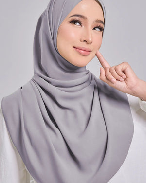 Woman wearing a gray hijab against a plain background