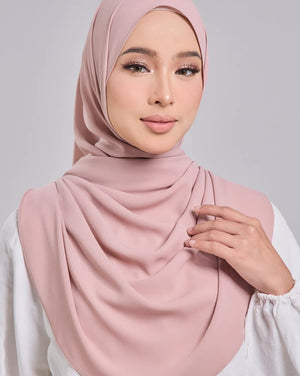 Woman wearing a pink hijab against a gray background