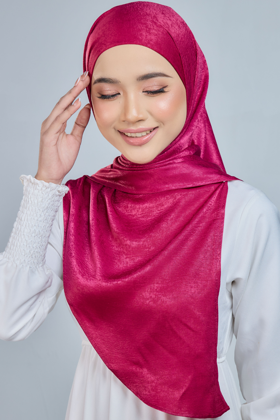 A person wearing a red half moon shaped shawl made of velvet satin with an adjustable tie back band.