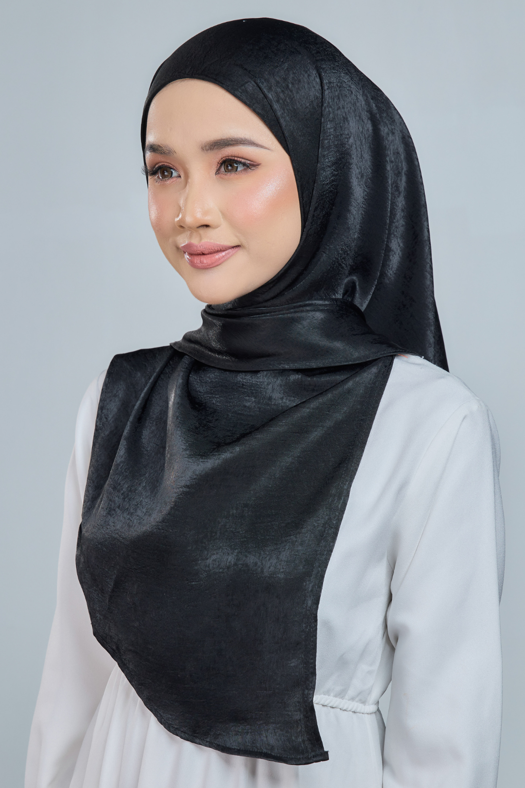 A person wearing a red half moon shaped shawl made of velvet satin with an adjustable tie back band.