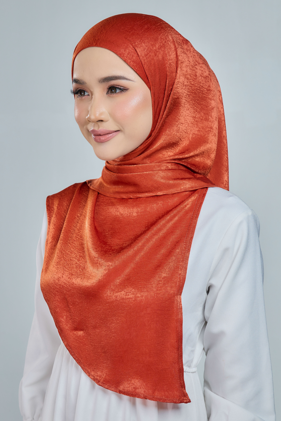 A person wearing a red half moon shaped shawl made of velvet satin with an adjustable tie back band.