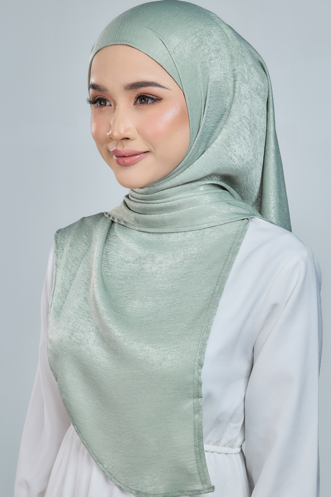 A person wearing a red half moon shaped shawl made of velvet satin with an adjustable tie back band.