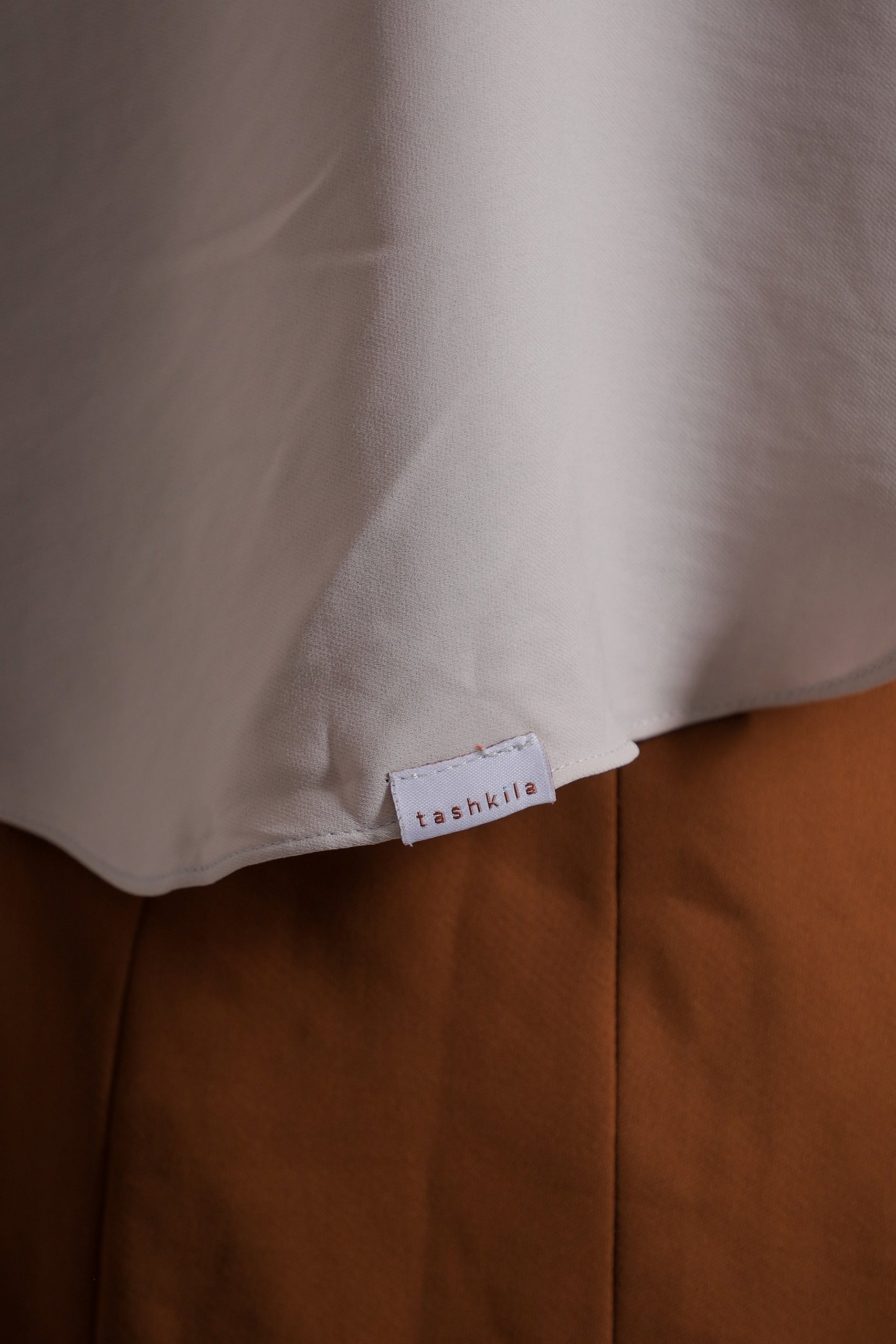 Close-up of a beige fabric with a 'tashika' label on a brown background