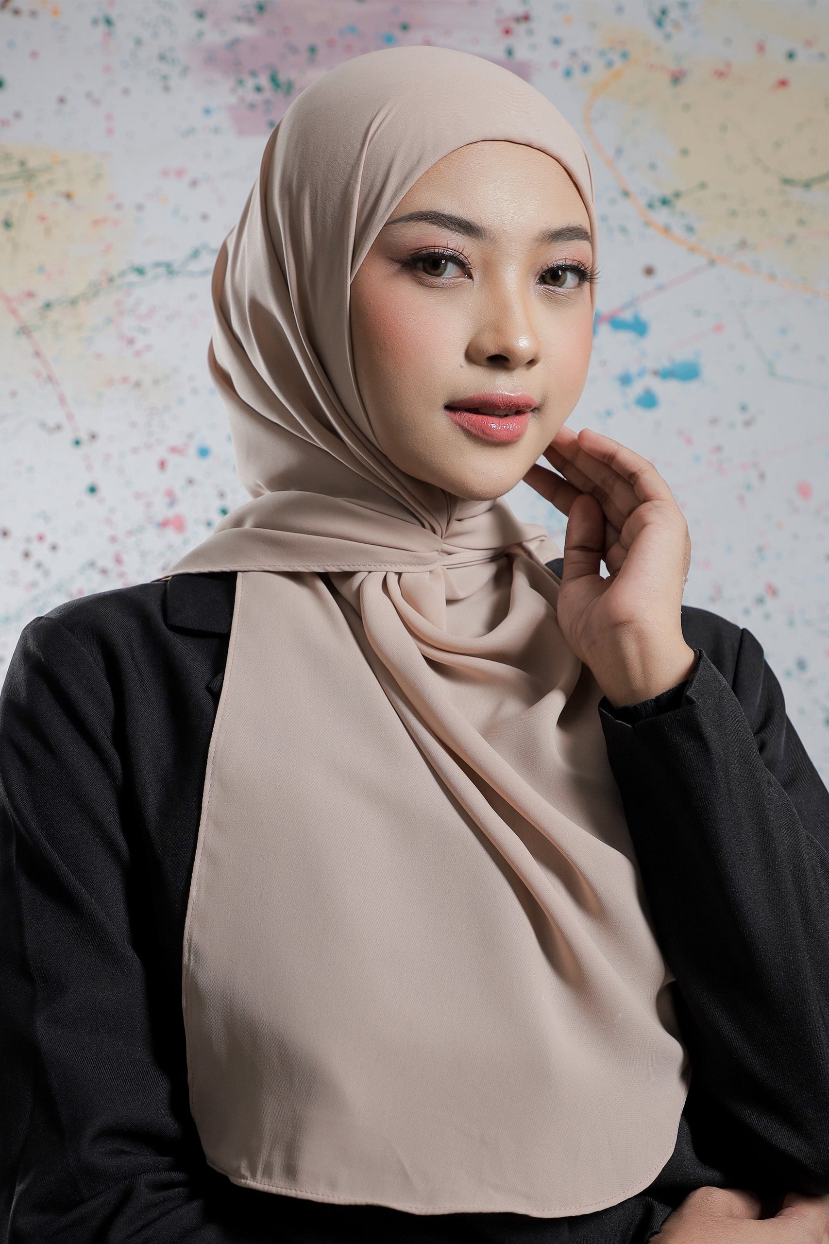 Woman wearing a beige hijab against a colorful abstract background