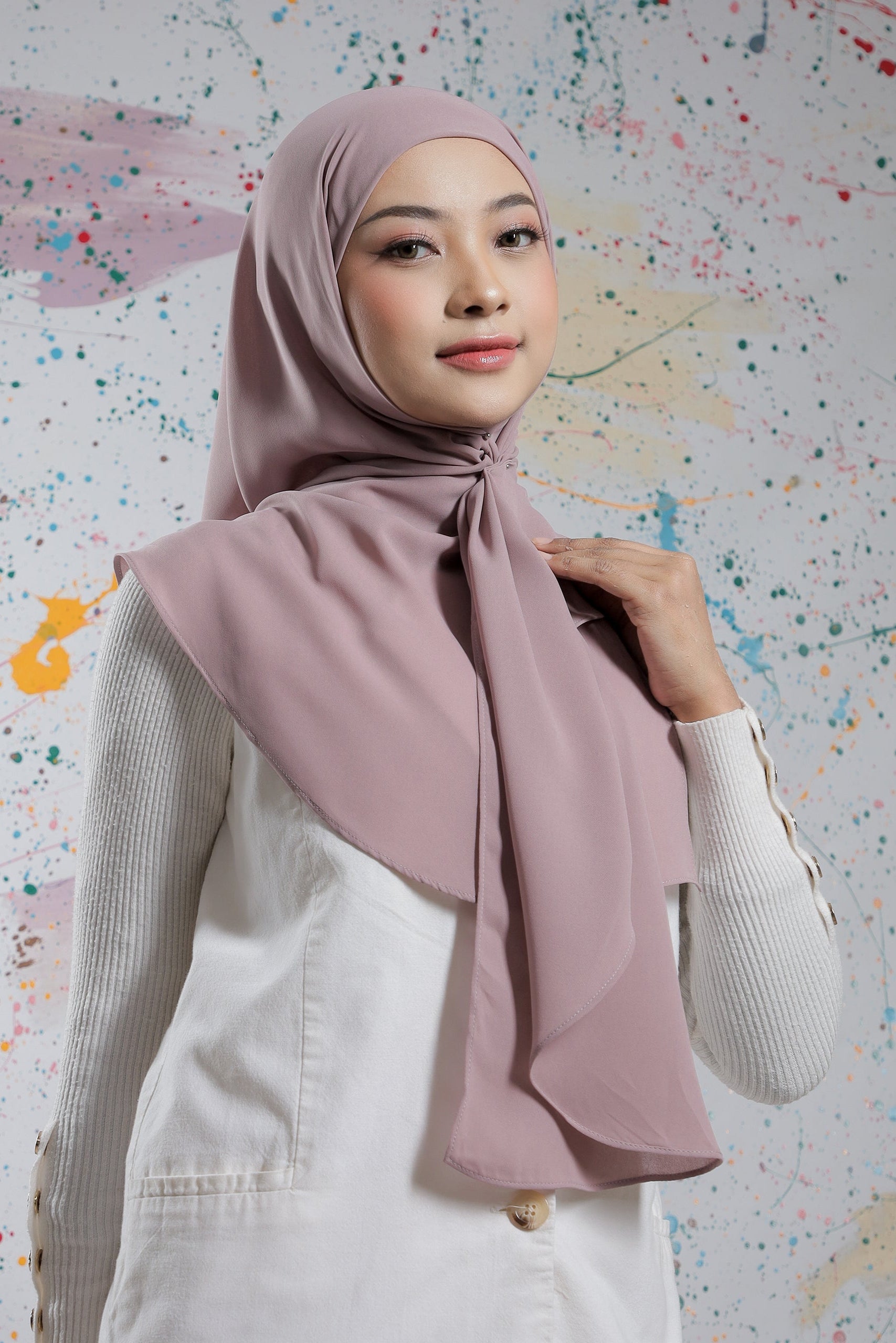 Woman wearing a light pink hijab against a colorful abstract background