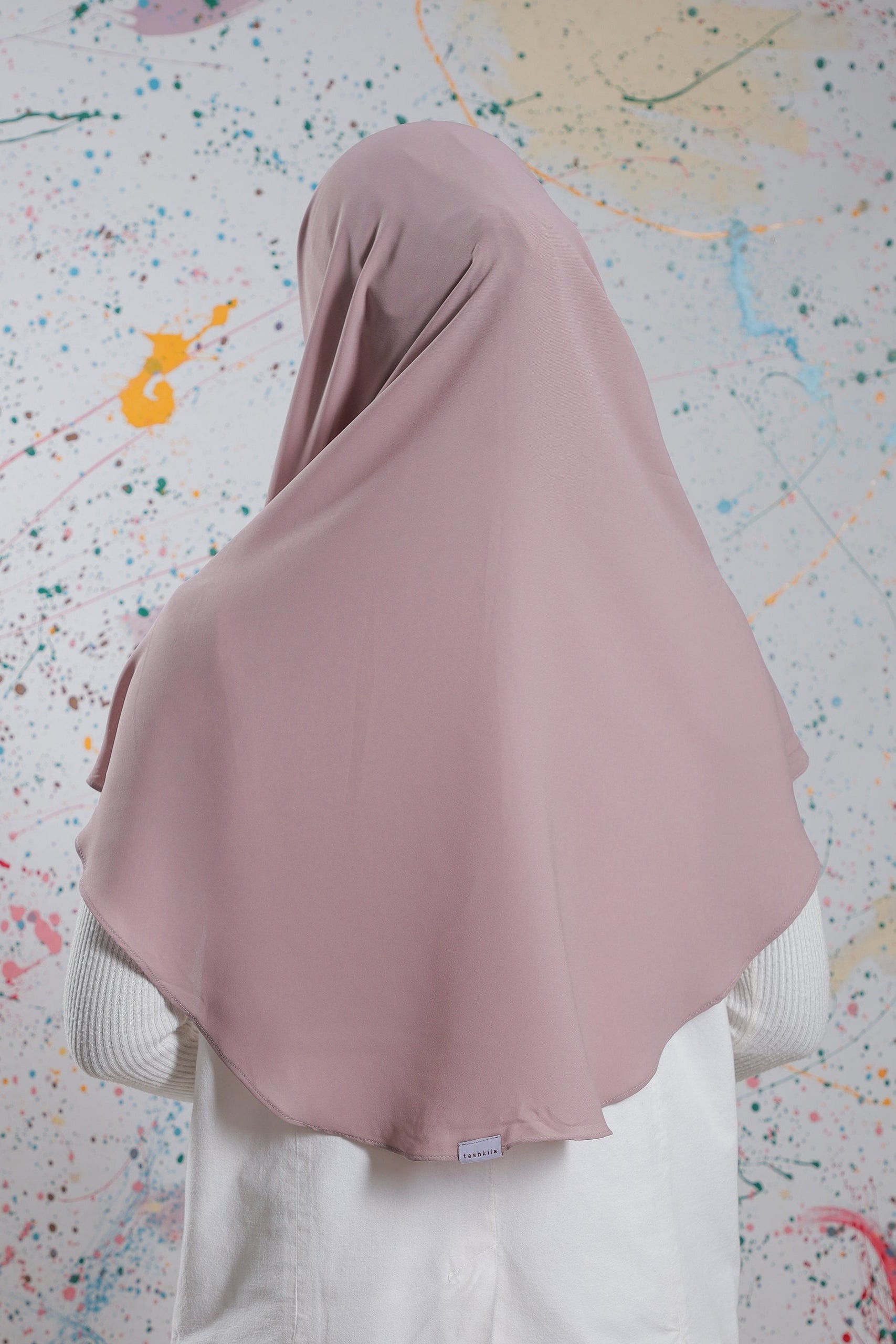 Person wearing a pink hijab against a colorful abstract background