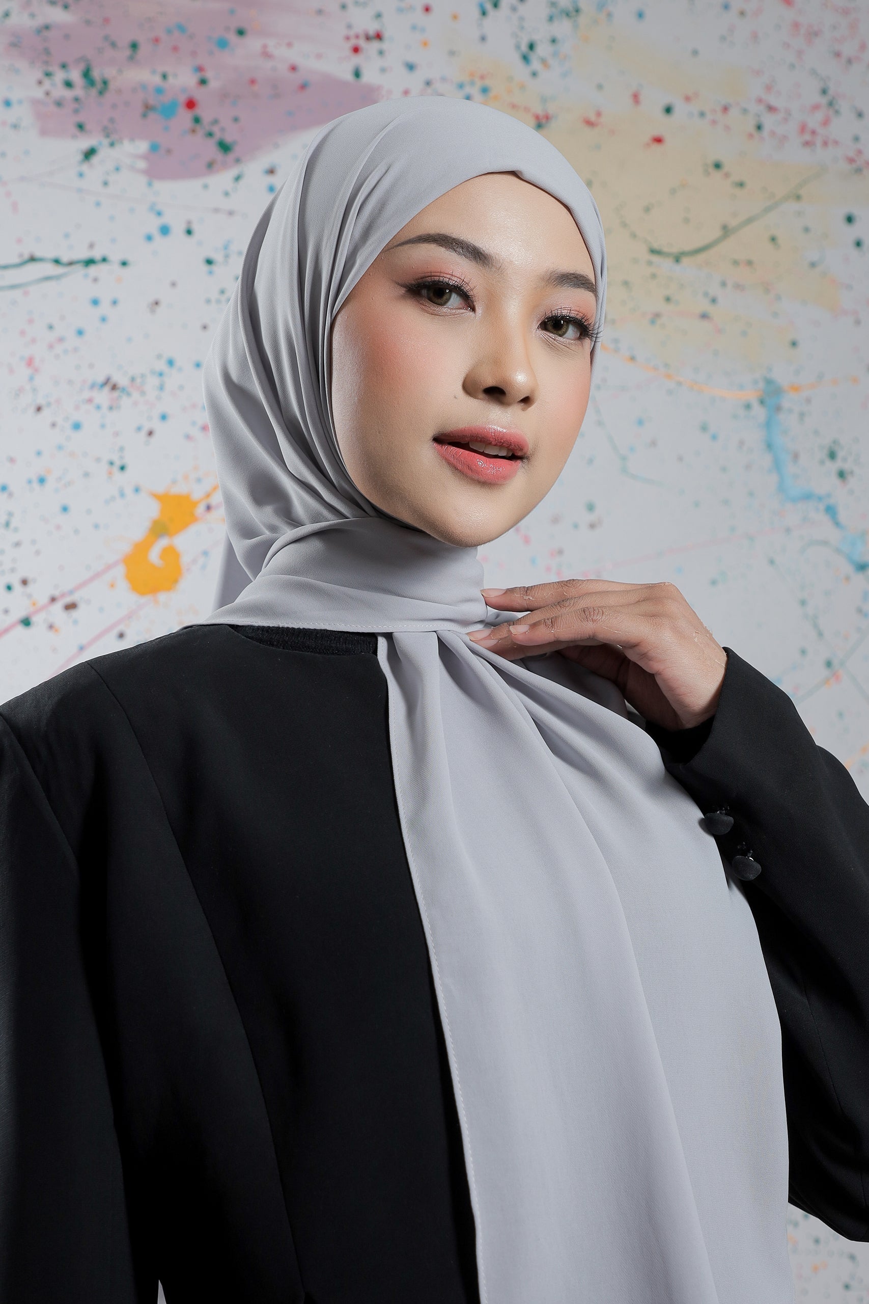 Woman wearing a gray hijab against a colorful abstract background