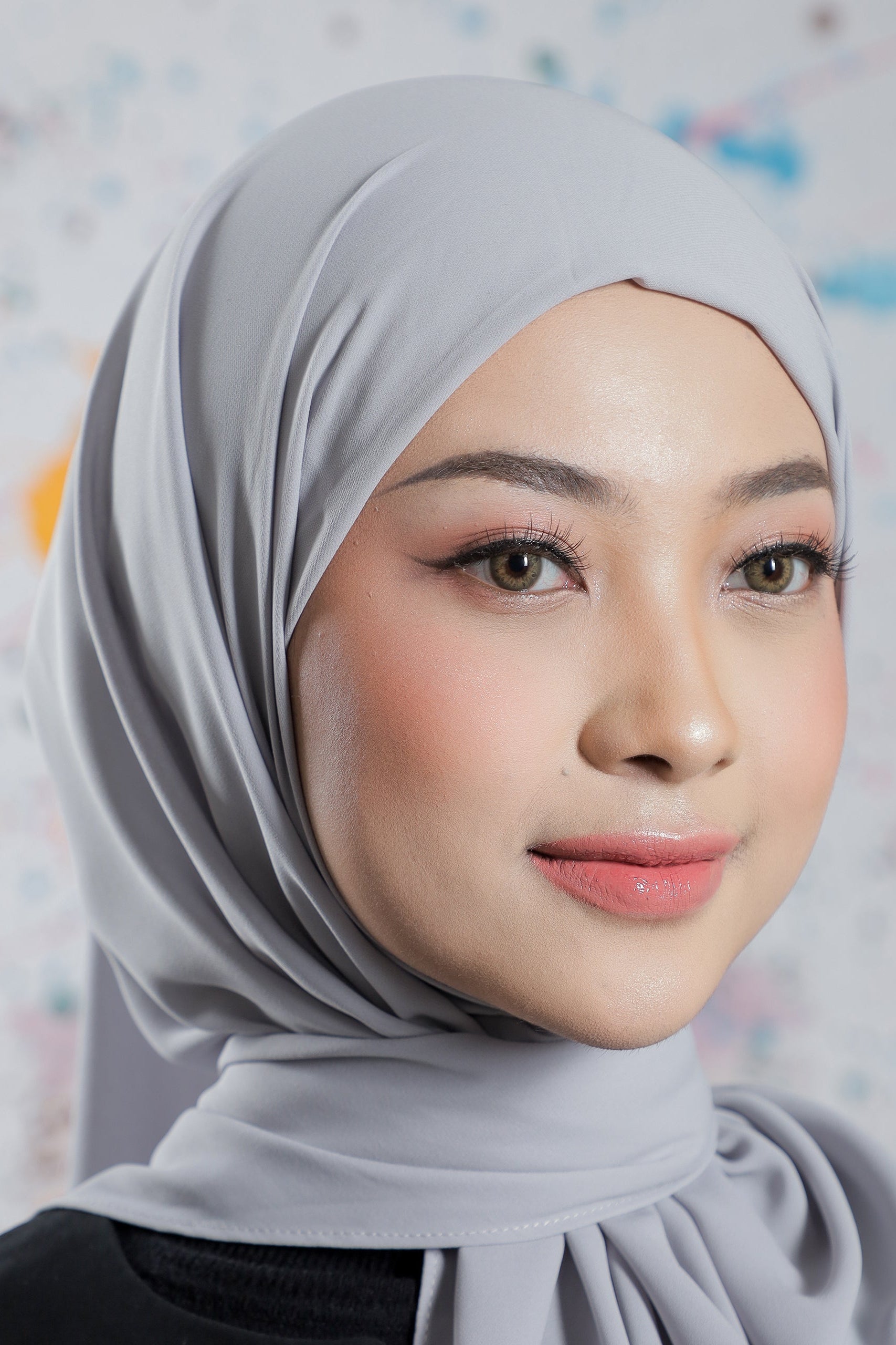 Woman wearing a light gray hijab with a blurred background