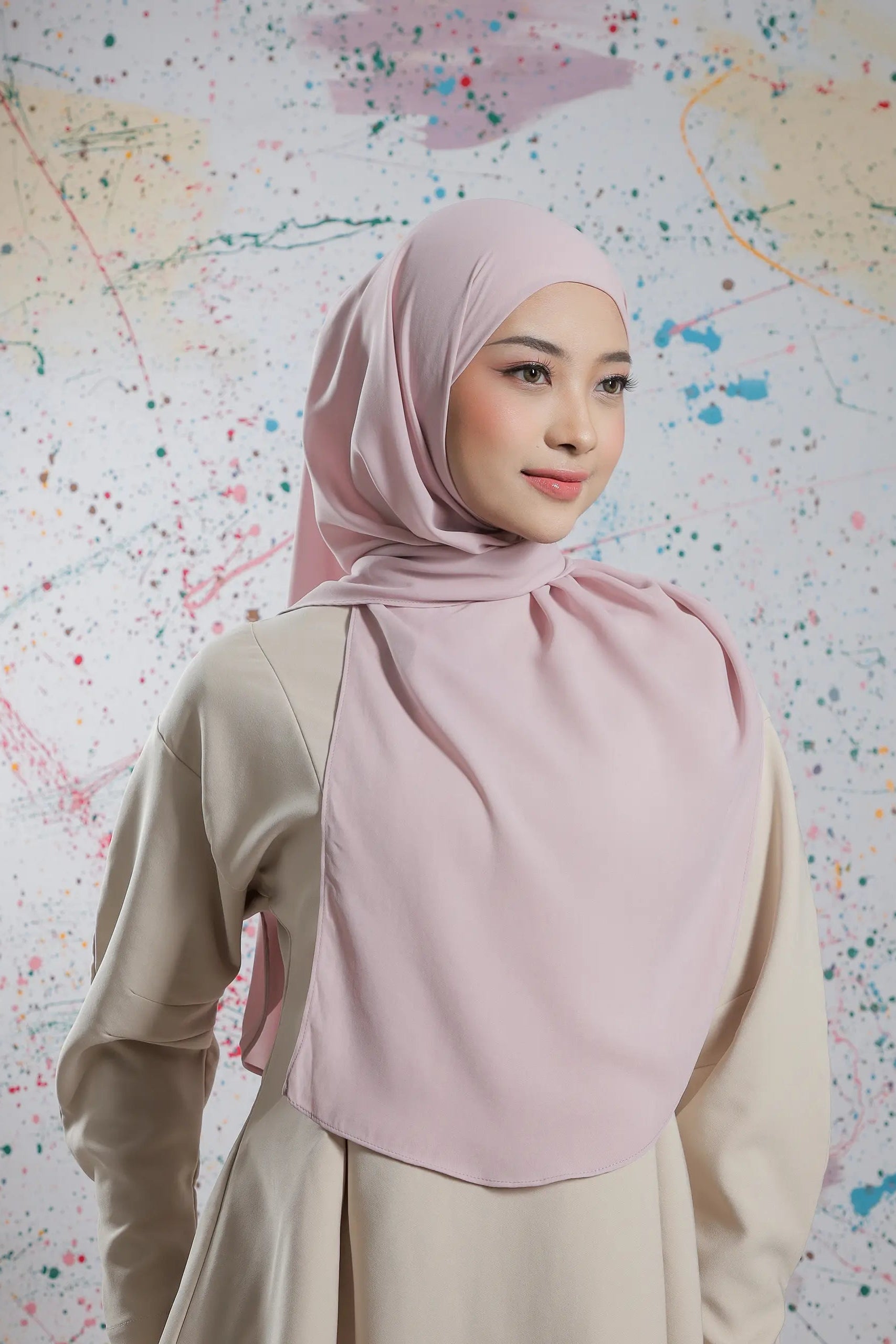 Woman wearing a pink hijab against a colorful abstract background