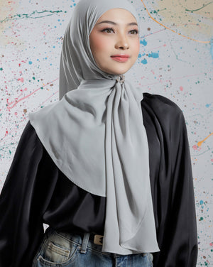 Woman wearing a gray hijab and black top against a colorful abstract background