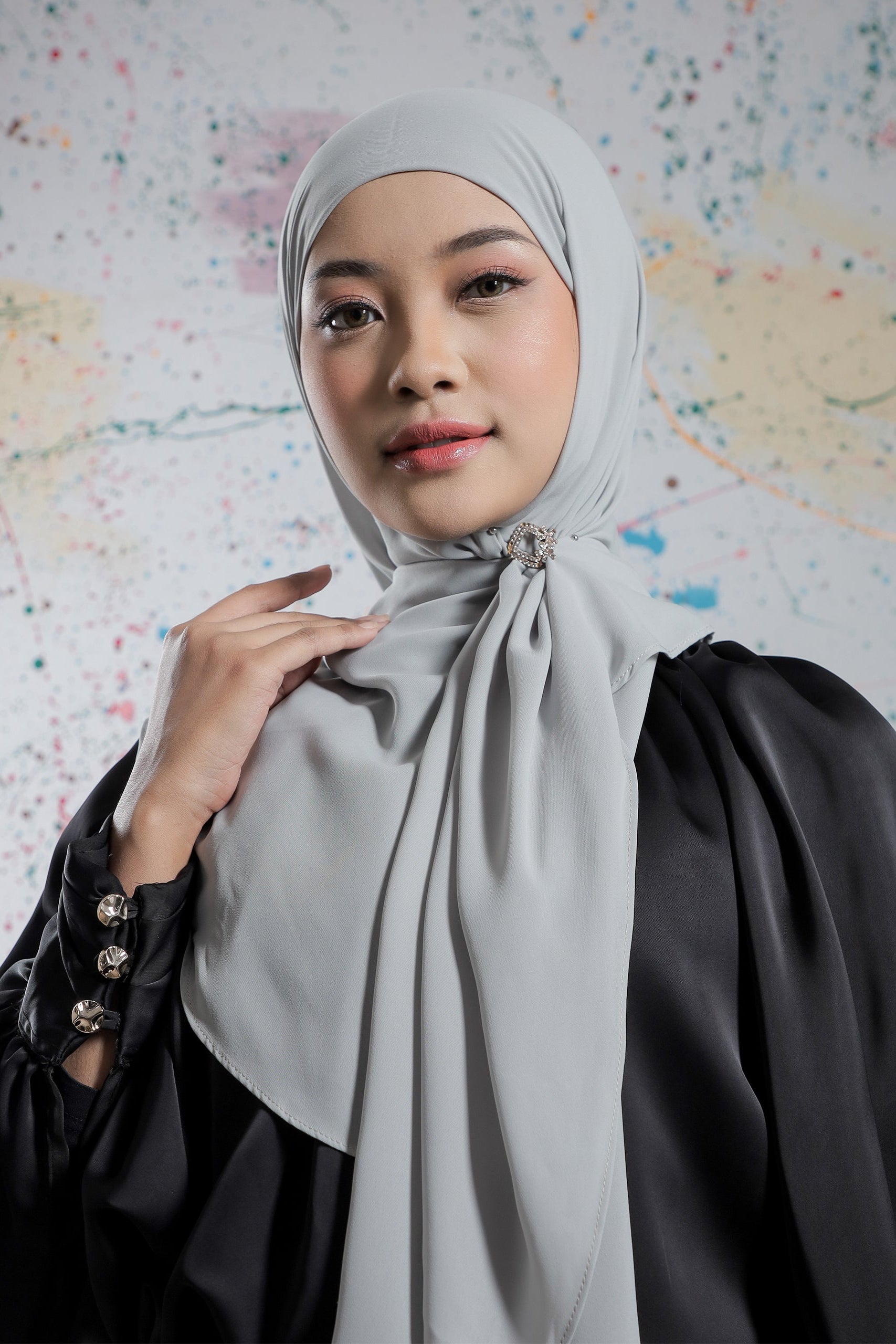 Woman wearing a light gray hijab against a world map background