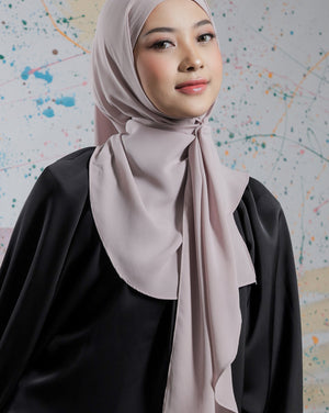Woman wearing a light pink hijab and black outfit against a colorful abstract background