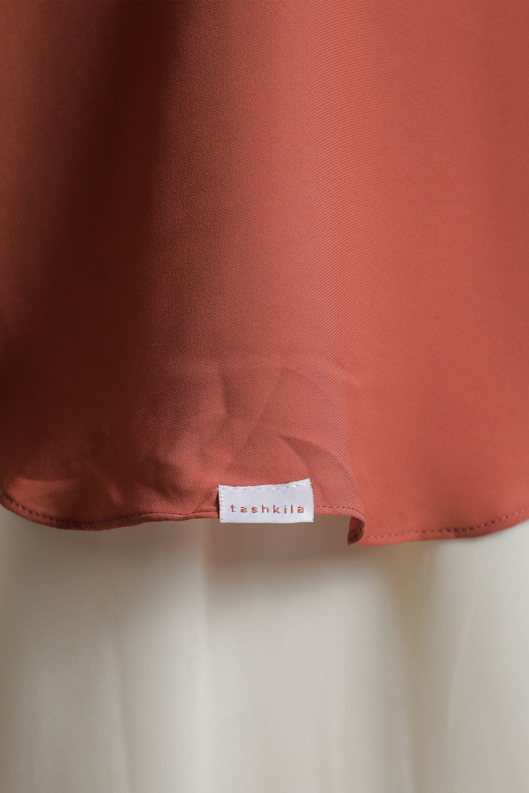 Close-up of a rust-colored fabric with a label on a light background