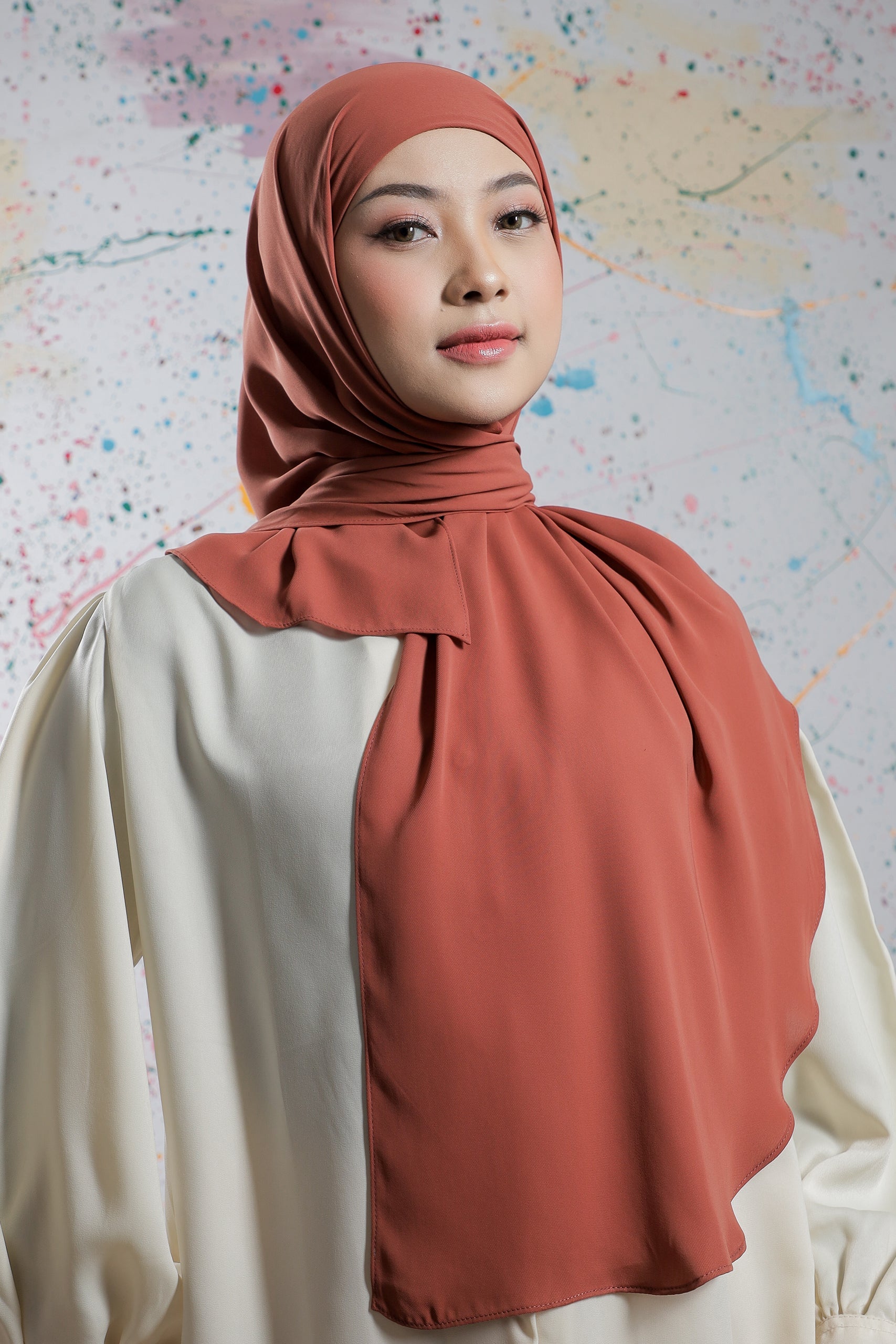 Woman wearing a rust-colored hijab against a map background