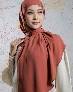 Woman wearing a rust-colored hijab against a colorful abstract background
