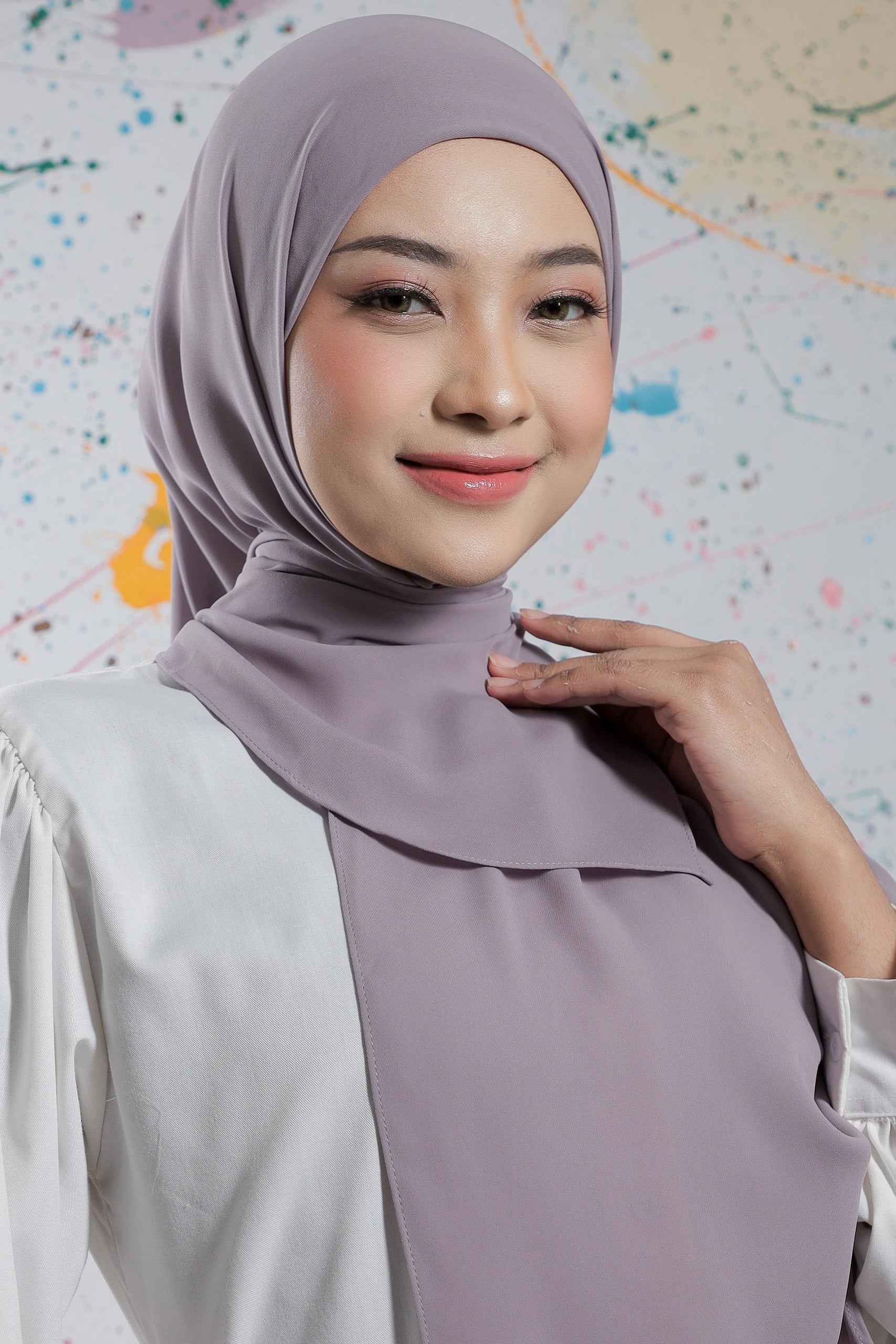 Woman wearing a light purple hijab against a colorful abstract background