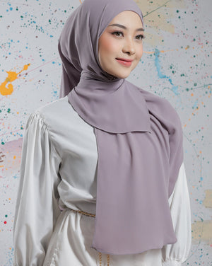 Woman wearing a light purple hijab and white outfit against a colorful abstract background