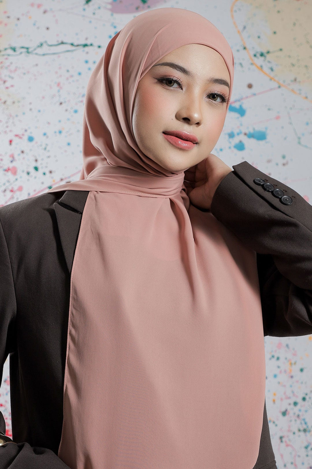 Woman wearing a pink hijab against a colorful abstract background
