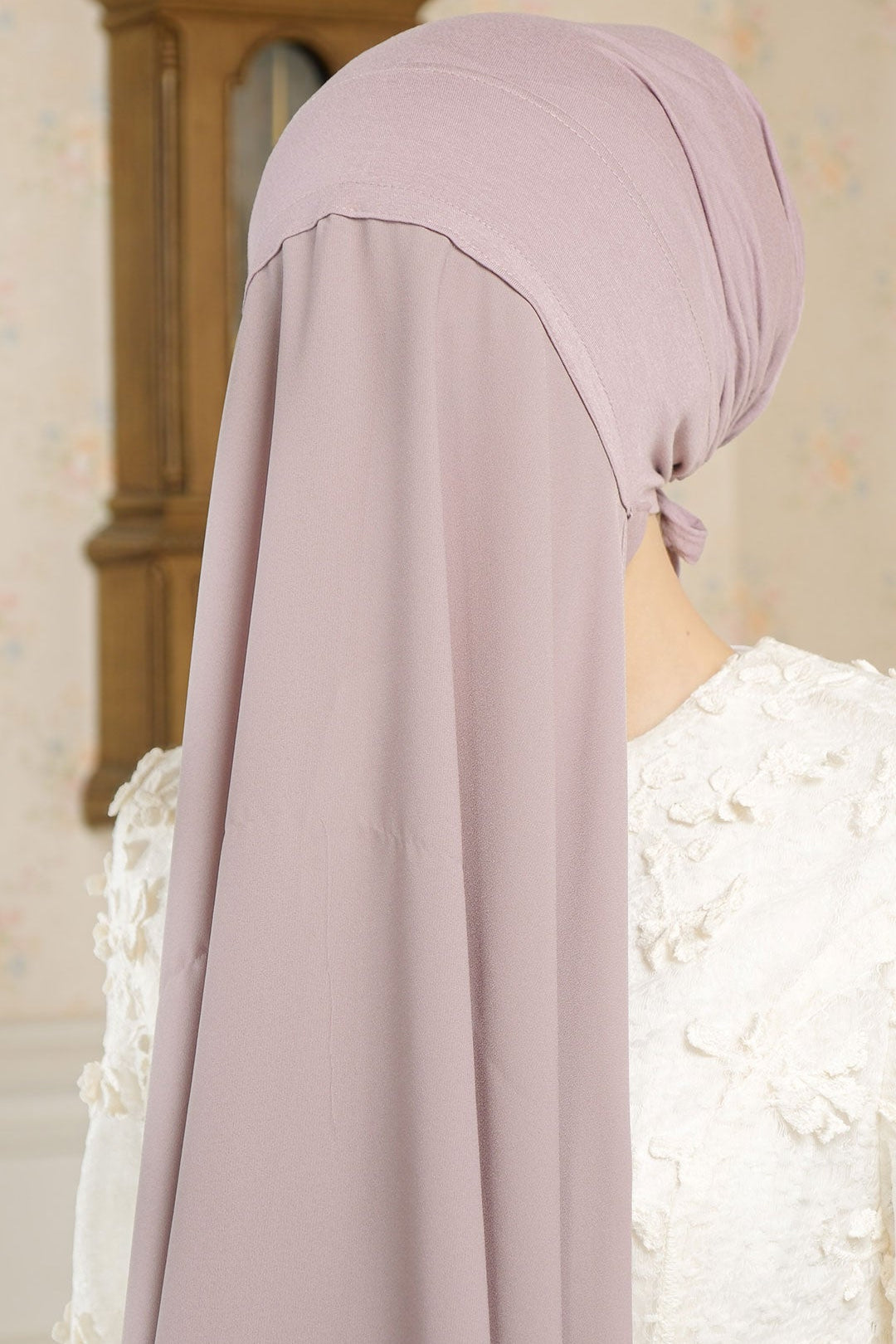 Person wearing a light purple hijab with a neutral background