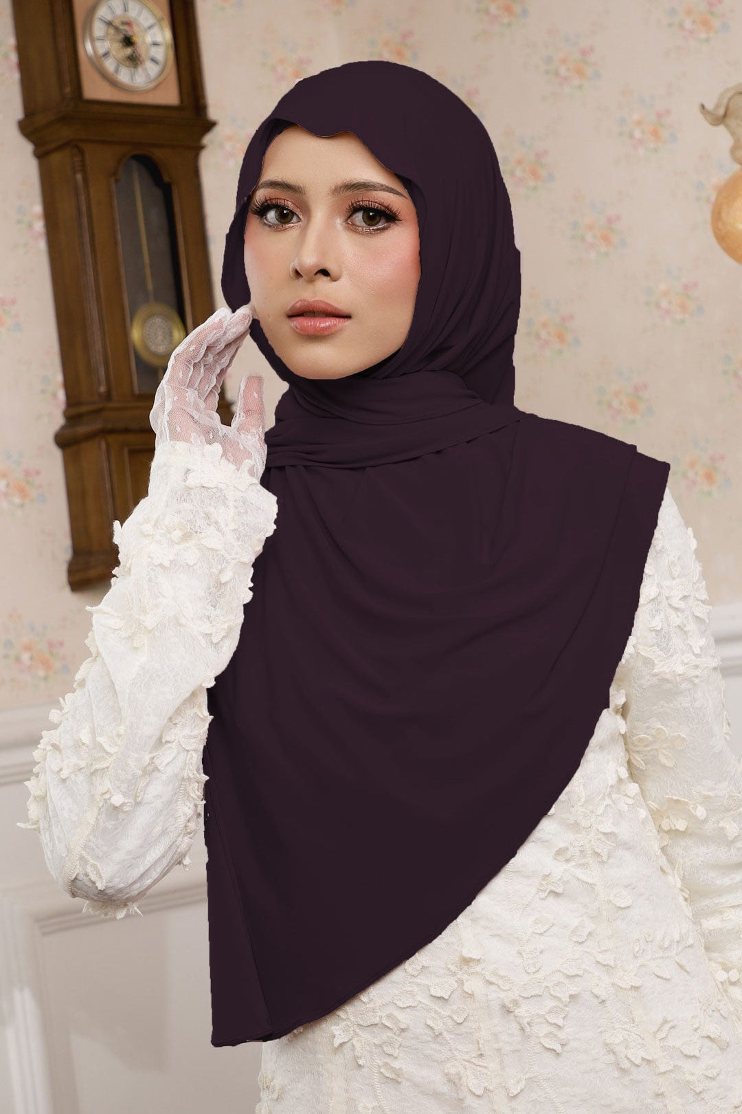 Woman wearing a dark hijab and white gloves in a decorated room with a clock.