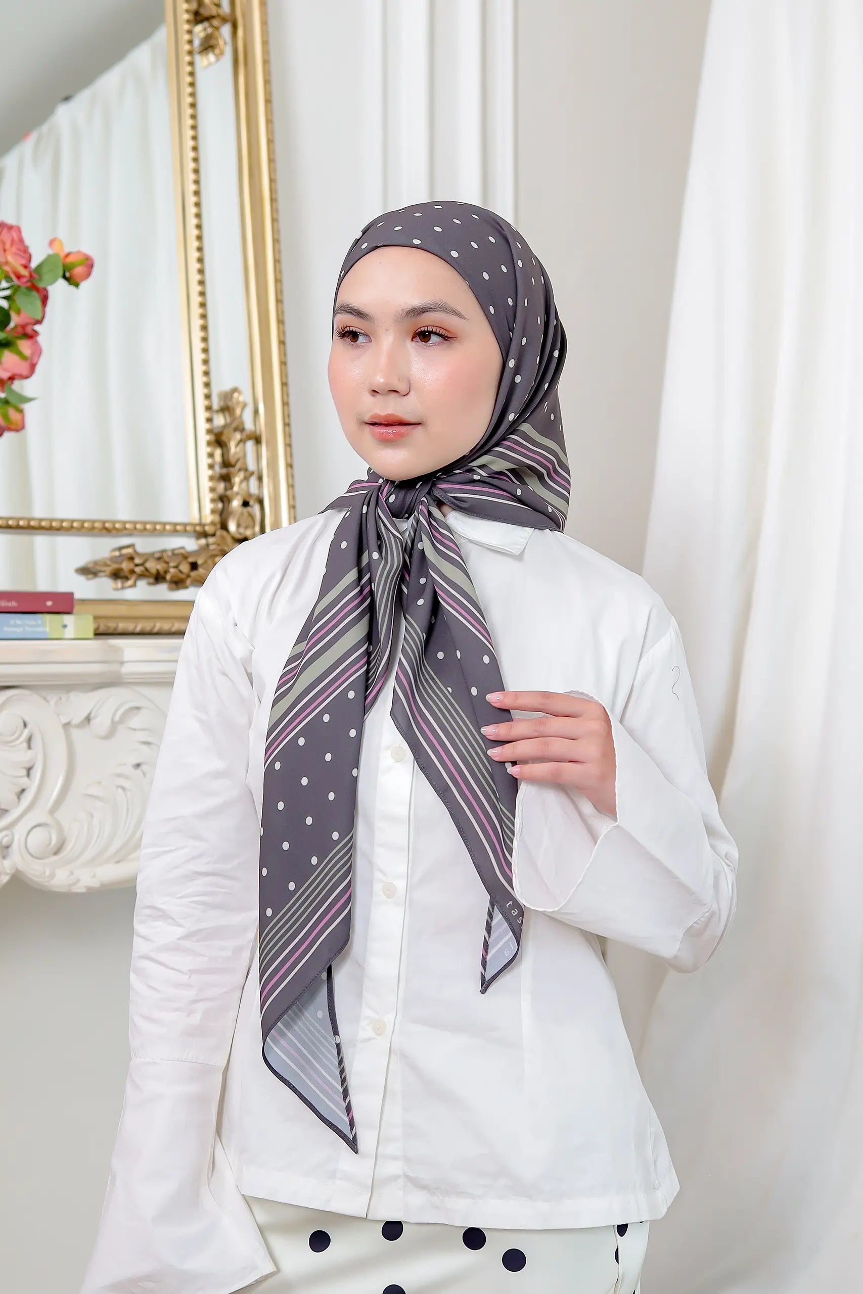 Woman wearing a patterned scarf in a room with decorative elements