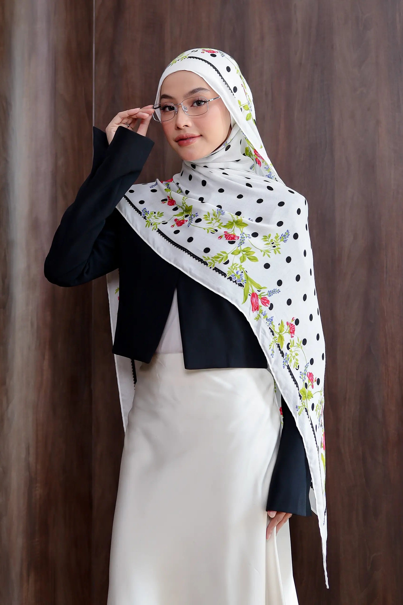 Woman wearing a floral hijab with a polka dot pattern against a wooden background