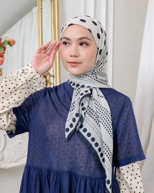Woman wearing a blue dress and patterned hijab in a decorative setting