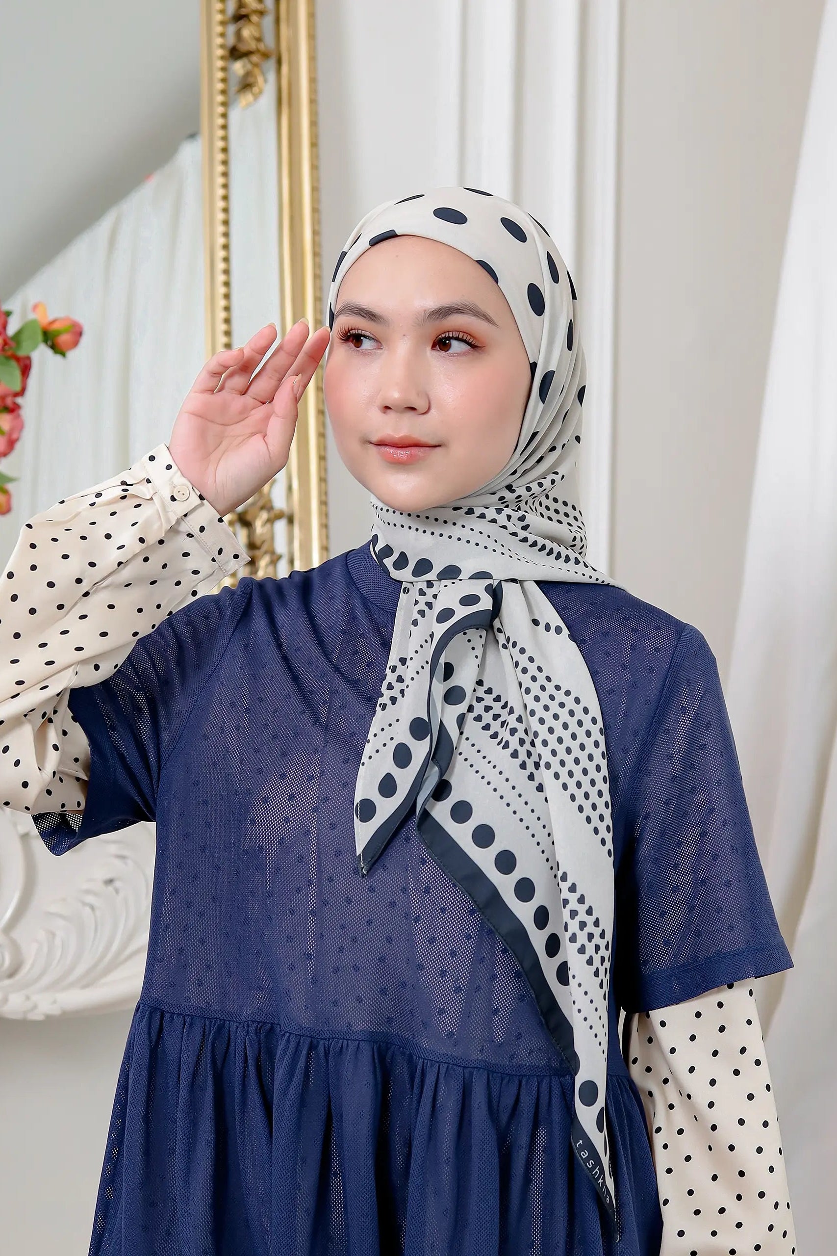 Woman wearing a blue dress and patterned hijab in a decorative setting