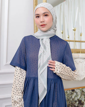 Woman wearing a blue dress with a patterned scarf in an elegant interior setting
