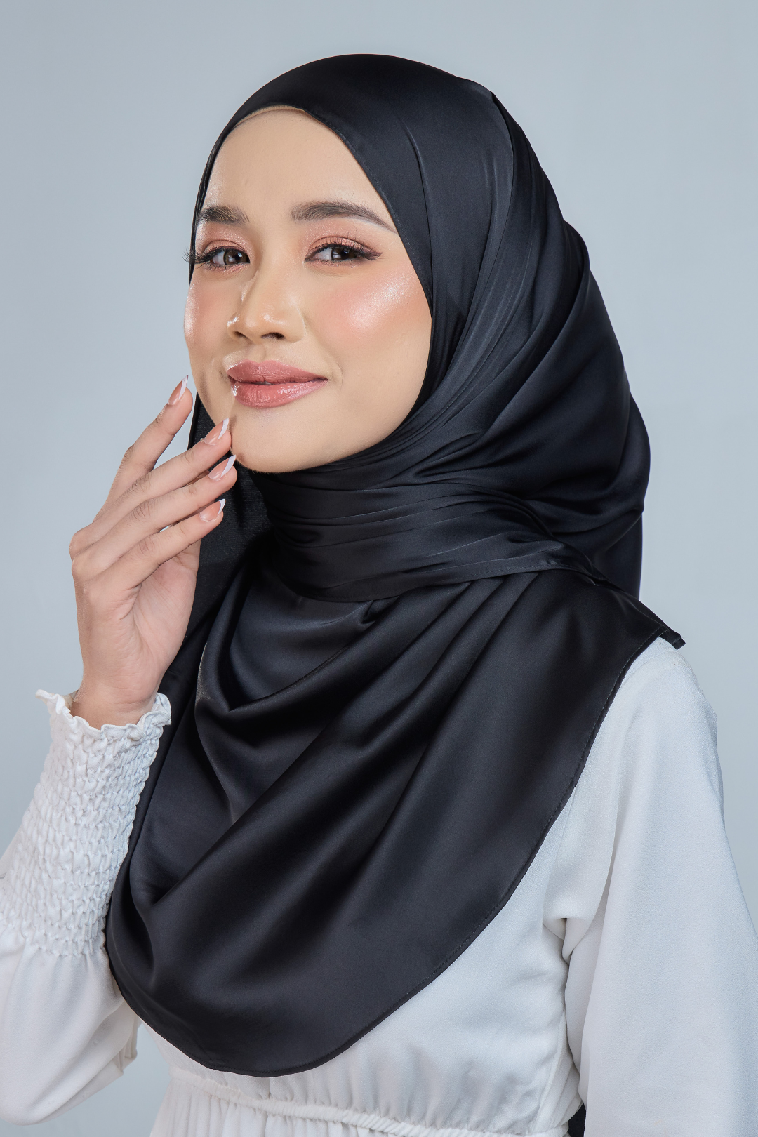 A woman wearing a black satin silk shawl draped over her shoulders, paired with a white outfit.