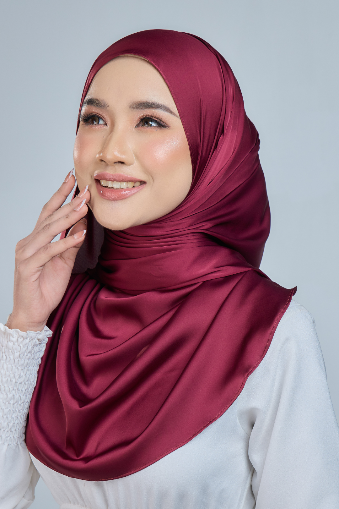 A woman wearing a fuschia satin silk shawl draped over her shoulders, paired with a white outfit.
