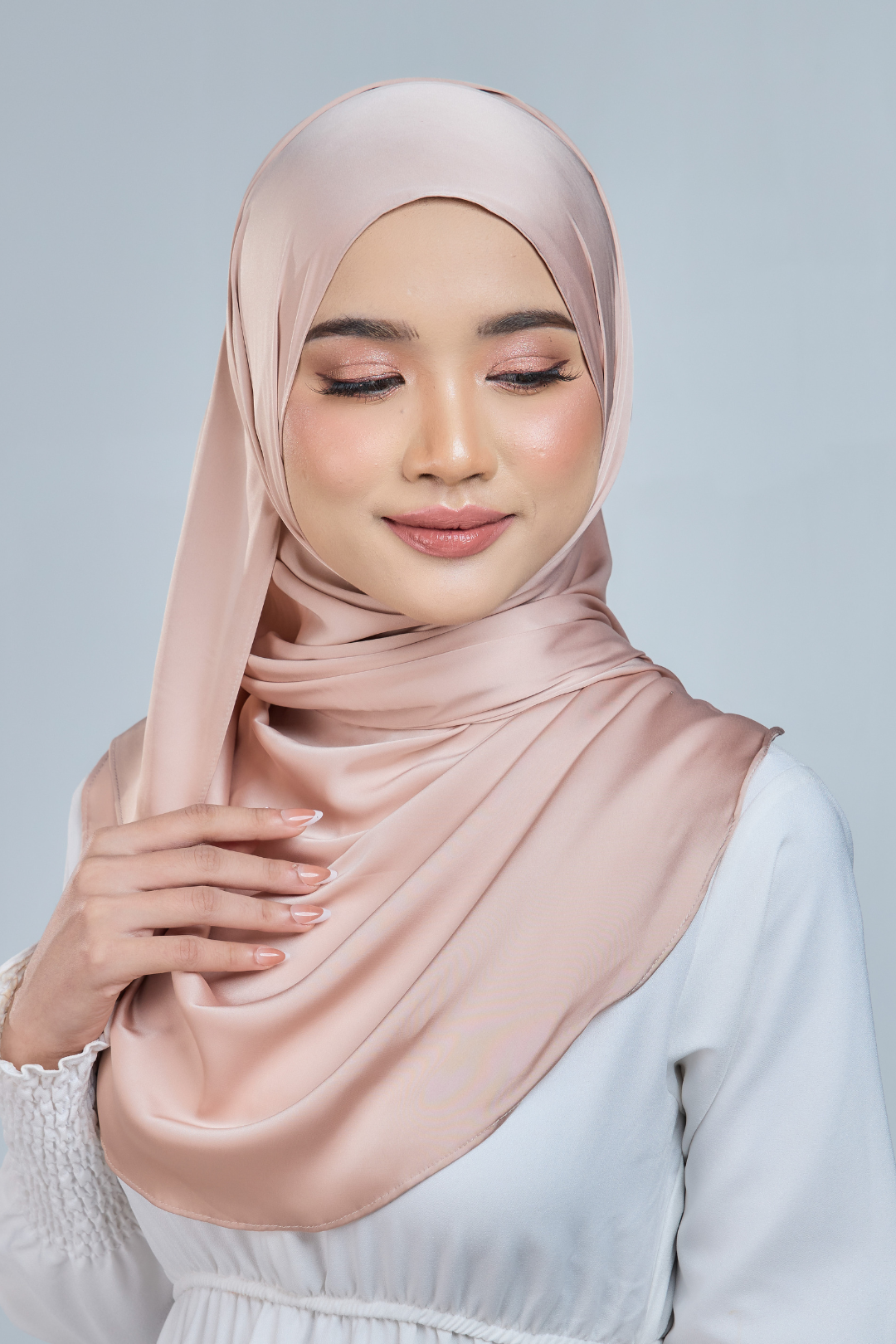 A woman wearing a beige satin silk shawl draped over her shoulders, paired with a white outfit.