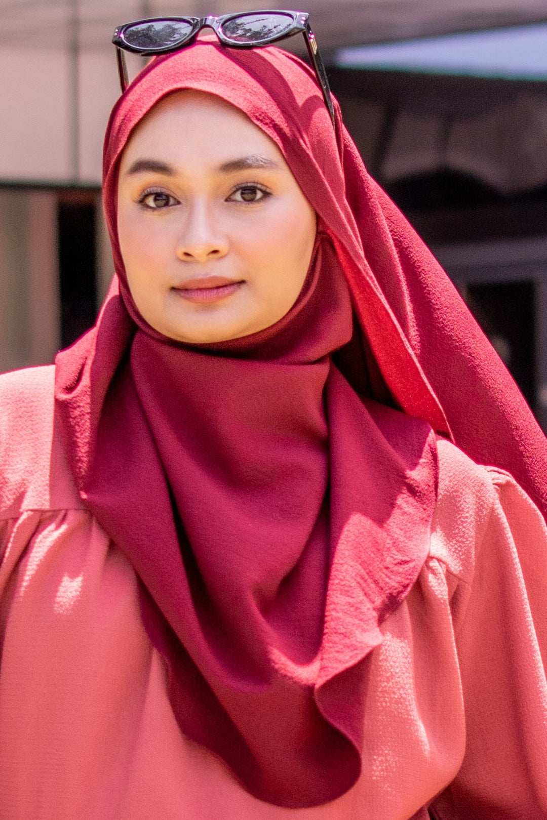 Woman wearing a red hijab and pink top outdoors