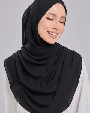 Woman wearing a black hijab and white top on a gray background