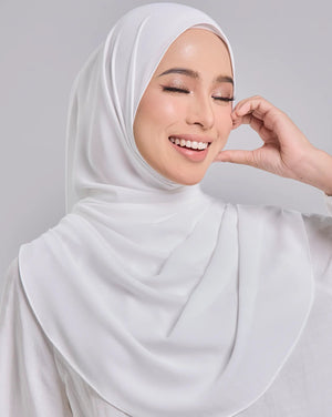 Woman wearing a white hijab against a gray background